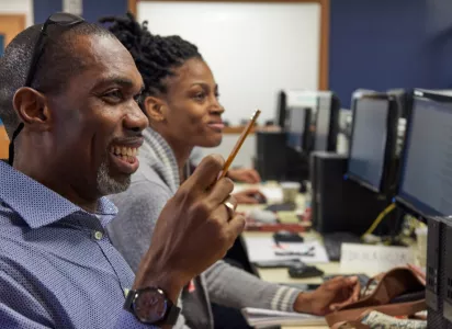 A group of Per Scholas students in a classroom setting, working on computers as part of technology training programs to advance economic equity.