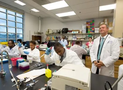 Students in lab coats training in a biotech lab at the BioTechnical Institute of Maryland.
