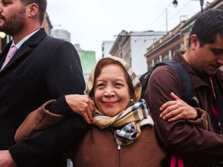 Elderly woman being supported by two adult men.