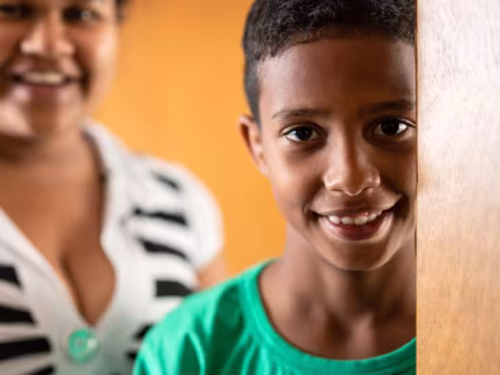 Child in focus laughing, with mother in the background.