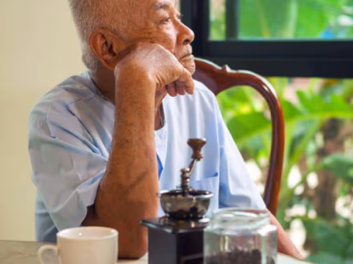 Elderly man with a distant look, sitting at a café table