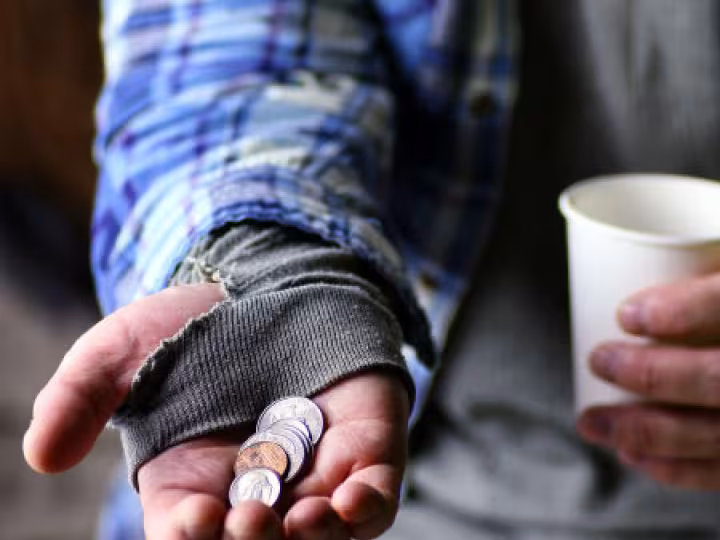 Homeless person’s hand holding coins.