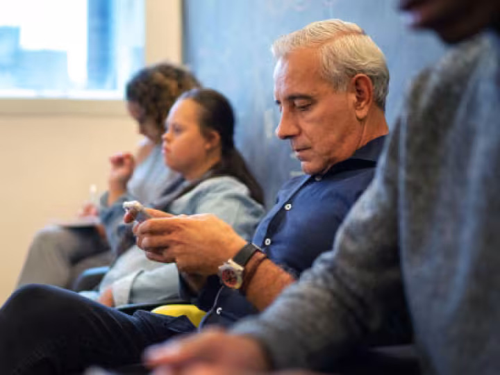 White-haired man looking at his phone.