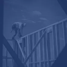 Construction worker atop the wooden frame of a half-completed building